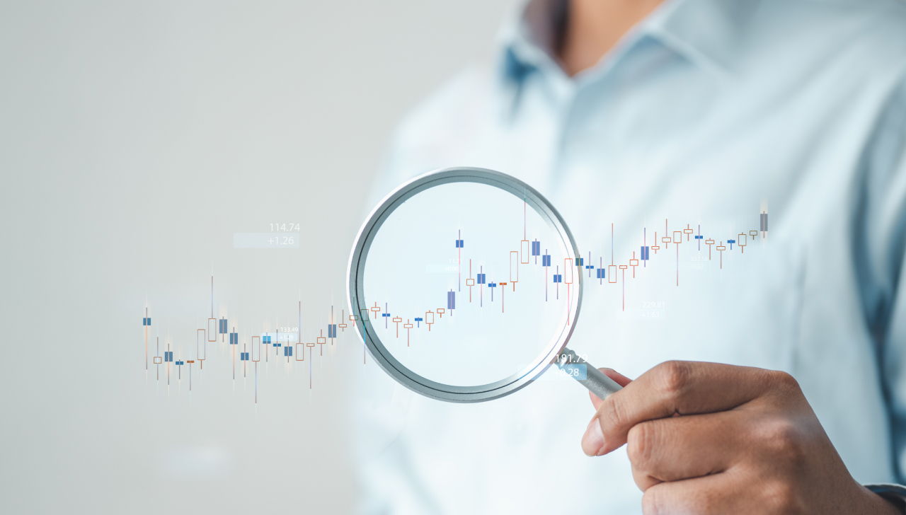 A person holds a magnifying glass over an upward trending chart, highlighting return data analysis and business insights