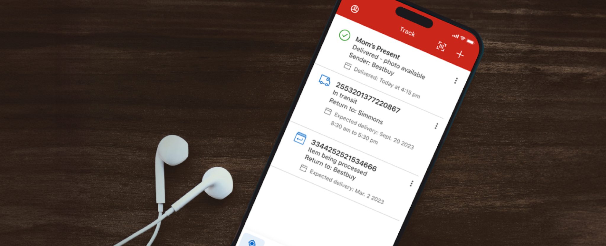 A cellphone is used to track multiple shipments in the Canada Post app. Earbuds rest beside the phone.