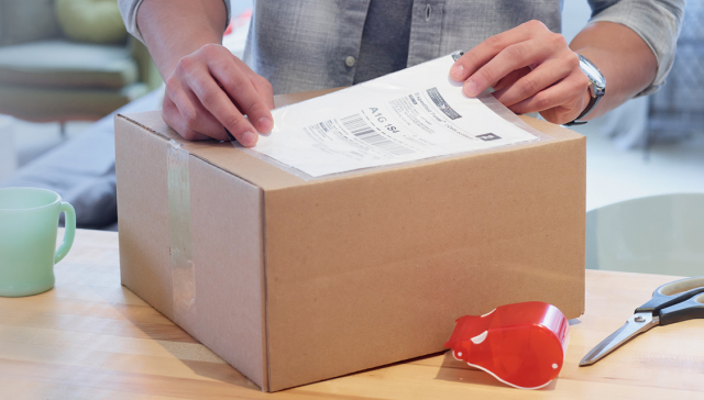 A man places a shipping label on a cardboard box.