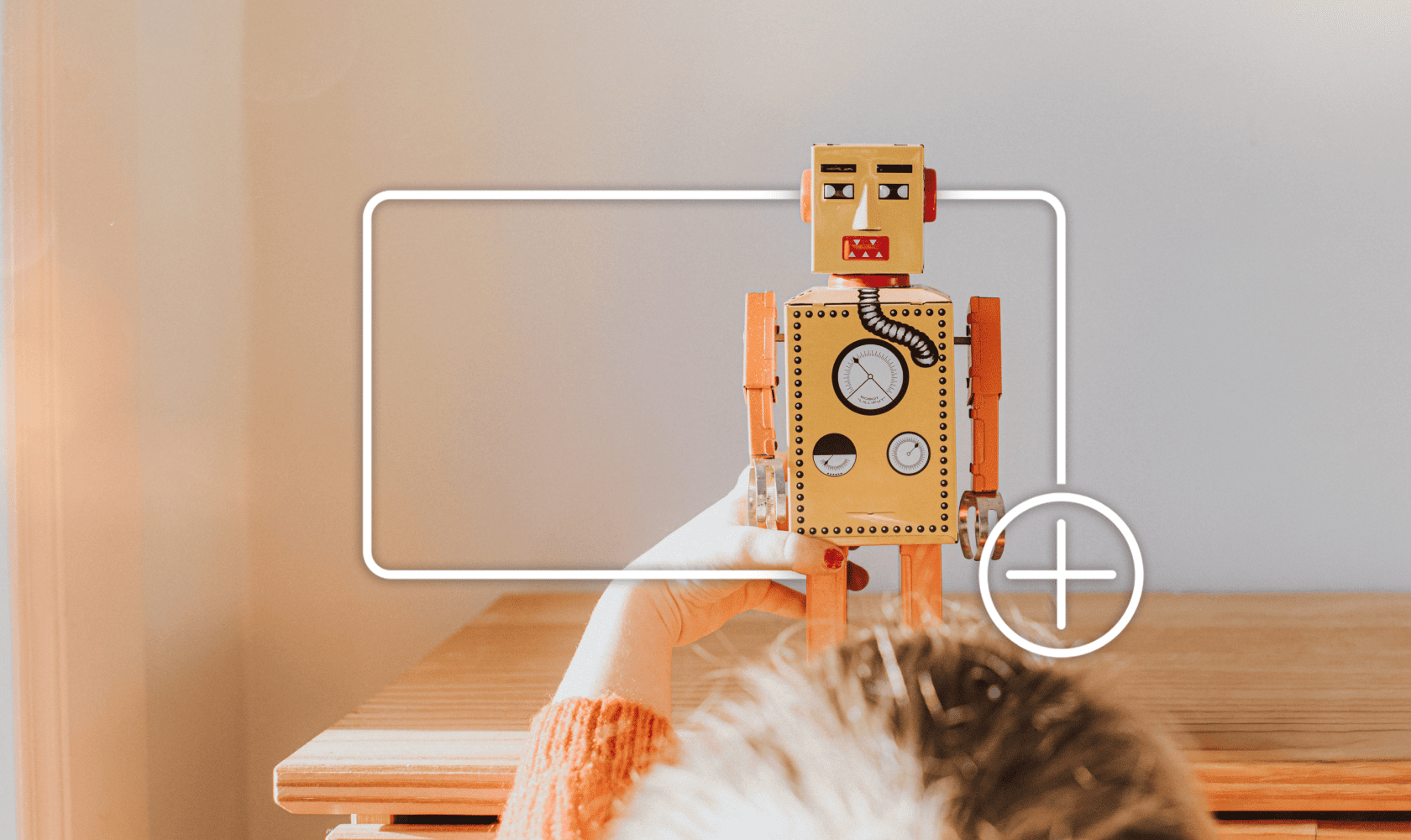 A child plays with a toy robot, framed by a white focus box with a plus icon, indicating adding to an online shopping cart.