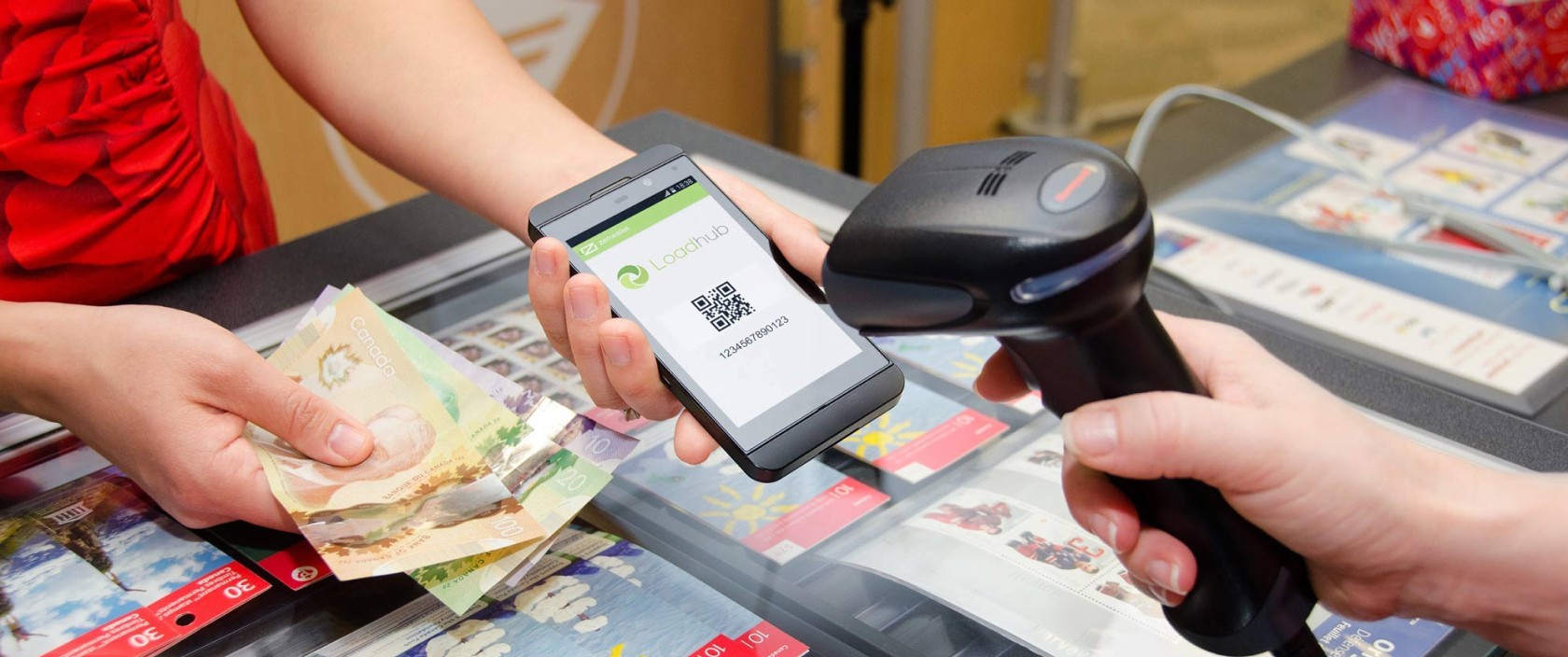 A woman makes a cash payment by presenting her Loadhub QR code at a Canada Post counter.