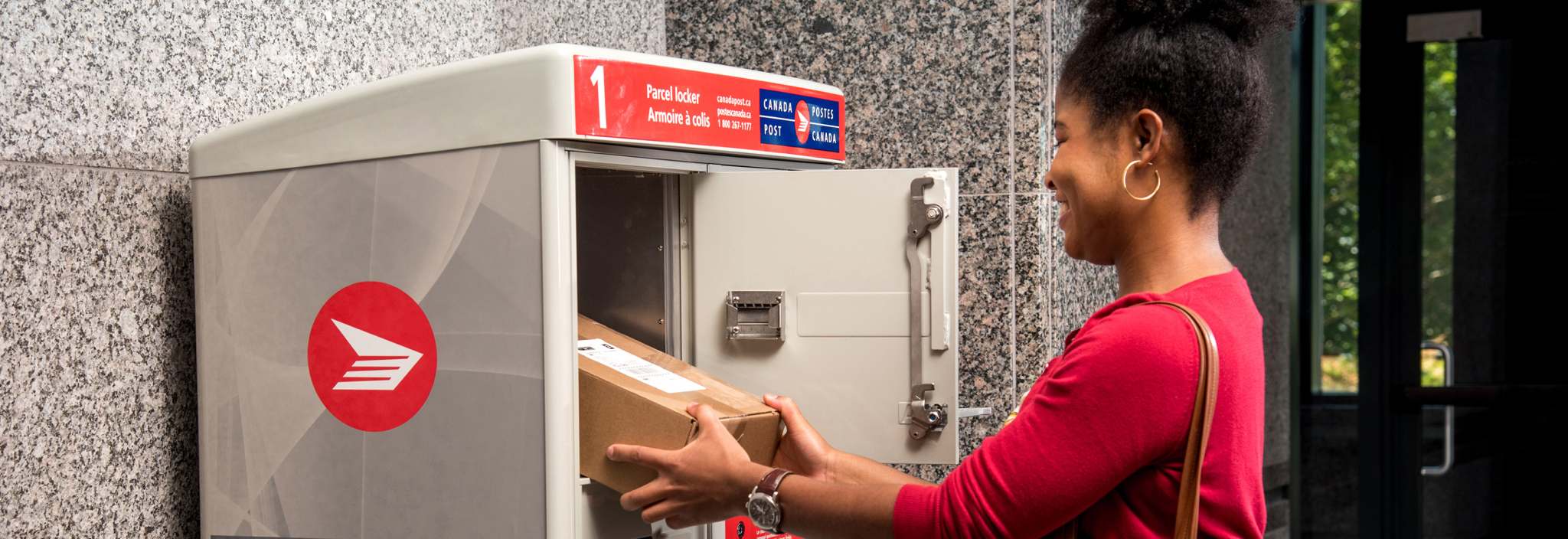 A woman retrieves her package from the Canada Post parcel locker in her apartment building’s mailroom.