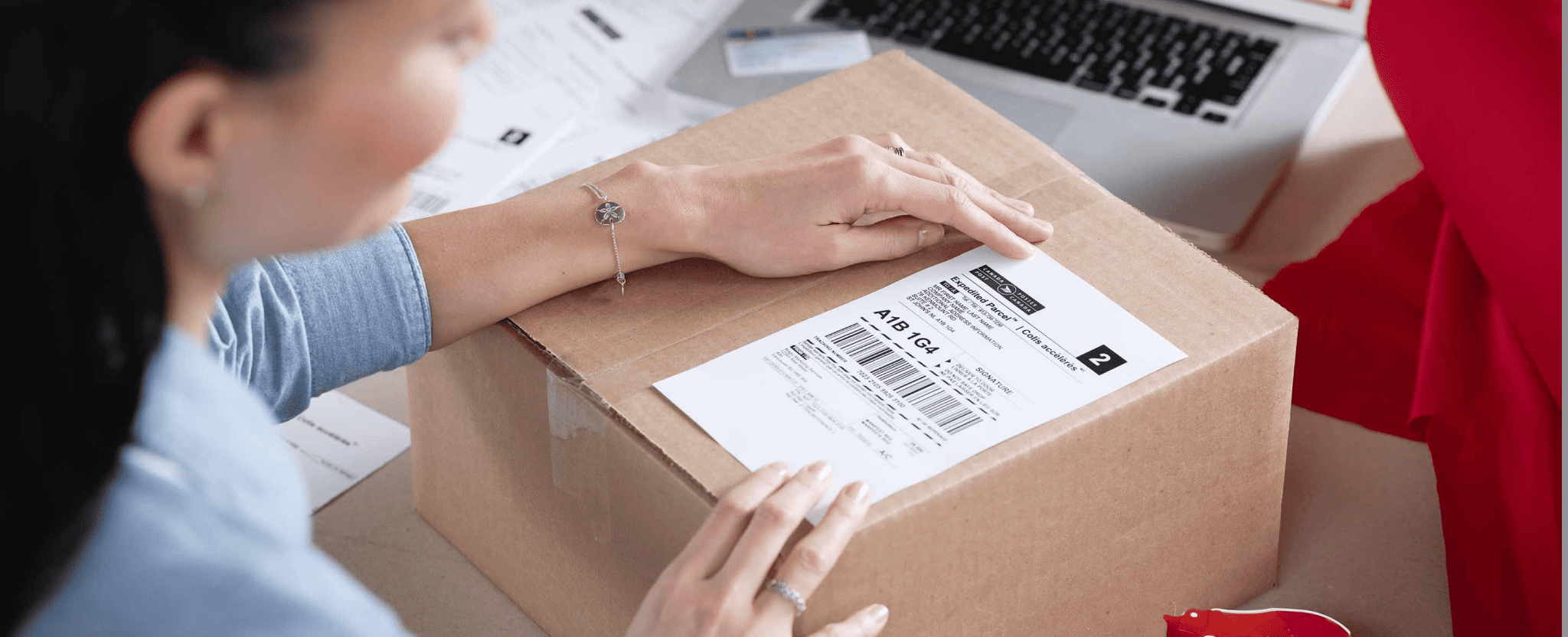 Woman applies a Canada Post return label to a package.