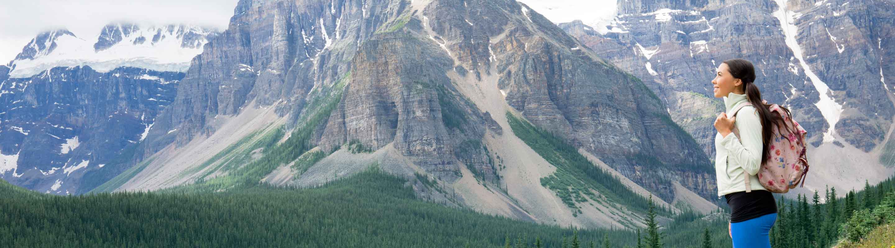 A young woman hikes near a mountain valley.