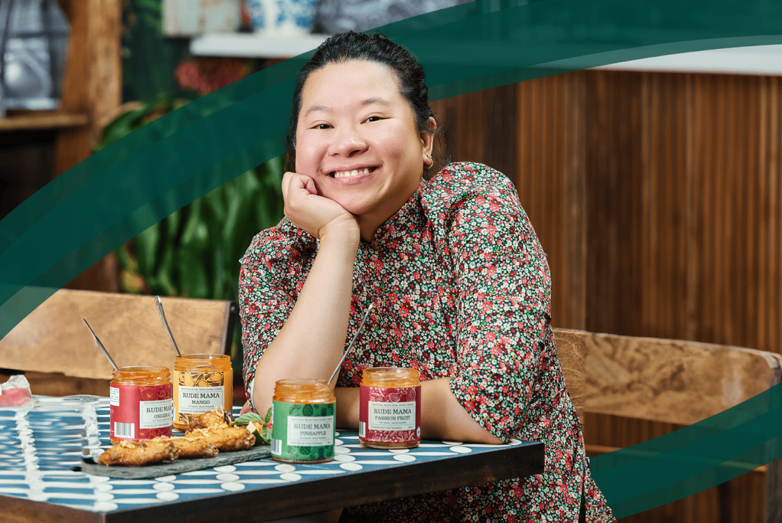 Attablée aux côtés de ses produits, VIan Nguyen, la fondatrice de Rude Mama Hotsauce, sourit à la caméra.
