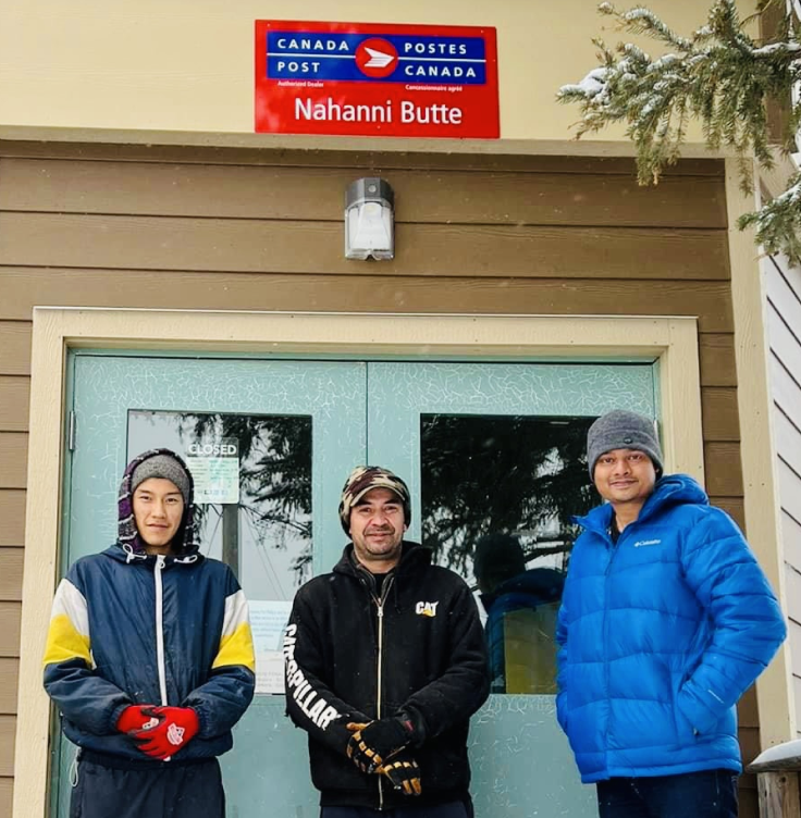 Brodie William Snider, Chief Steve Vital and Band Manager Soham Srimani stand in front of the entrance door of the Canada Post Nahanni Butte post office.