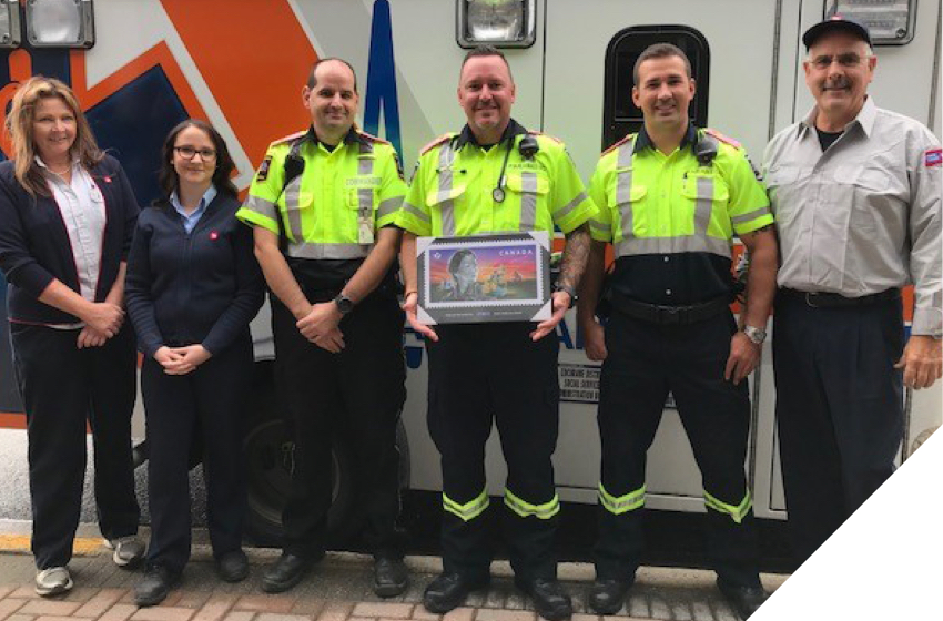 Canada Post employees present a commemorative plaque of the Emergency Responders stamp to paramedics in Timmins, Ont.