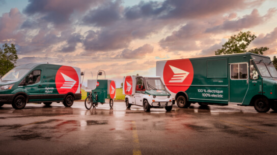 Canada Post hybrid and electric delivery vehicles parked in a row. 