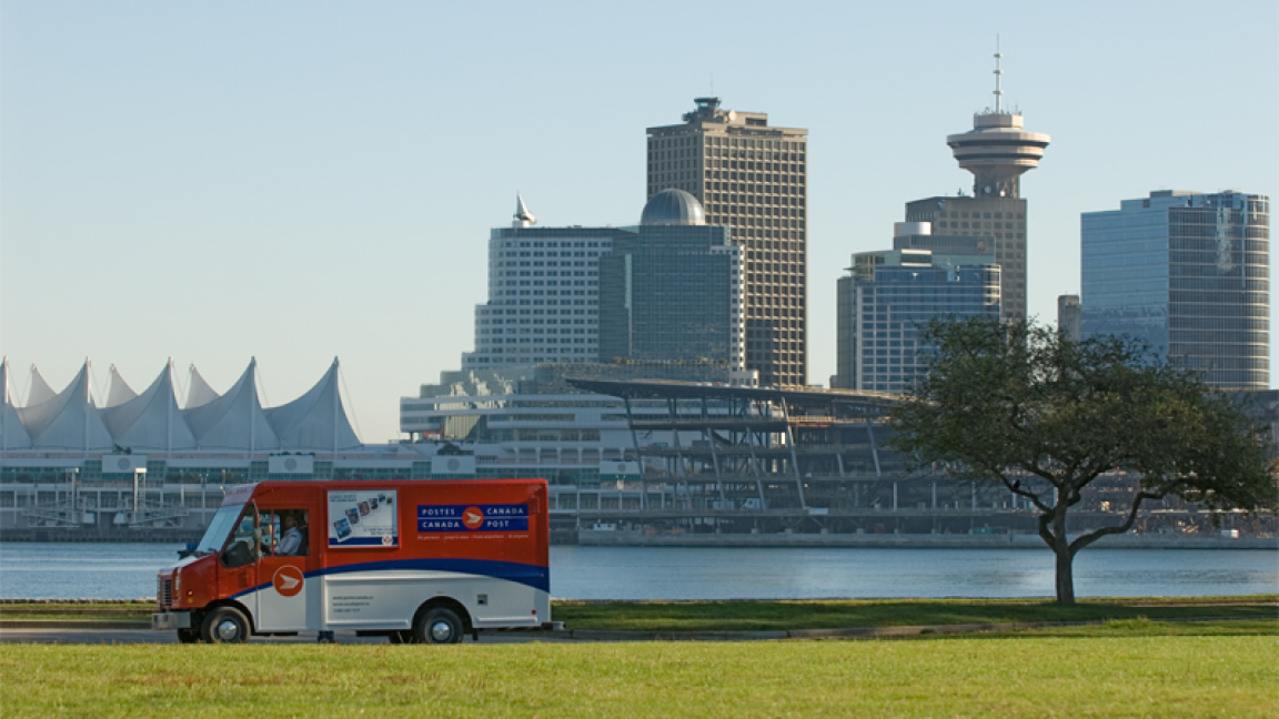 A Canada Post truck drives along Coal Harbour with the Vancouver city skyline in the background