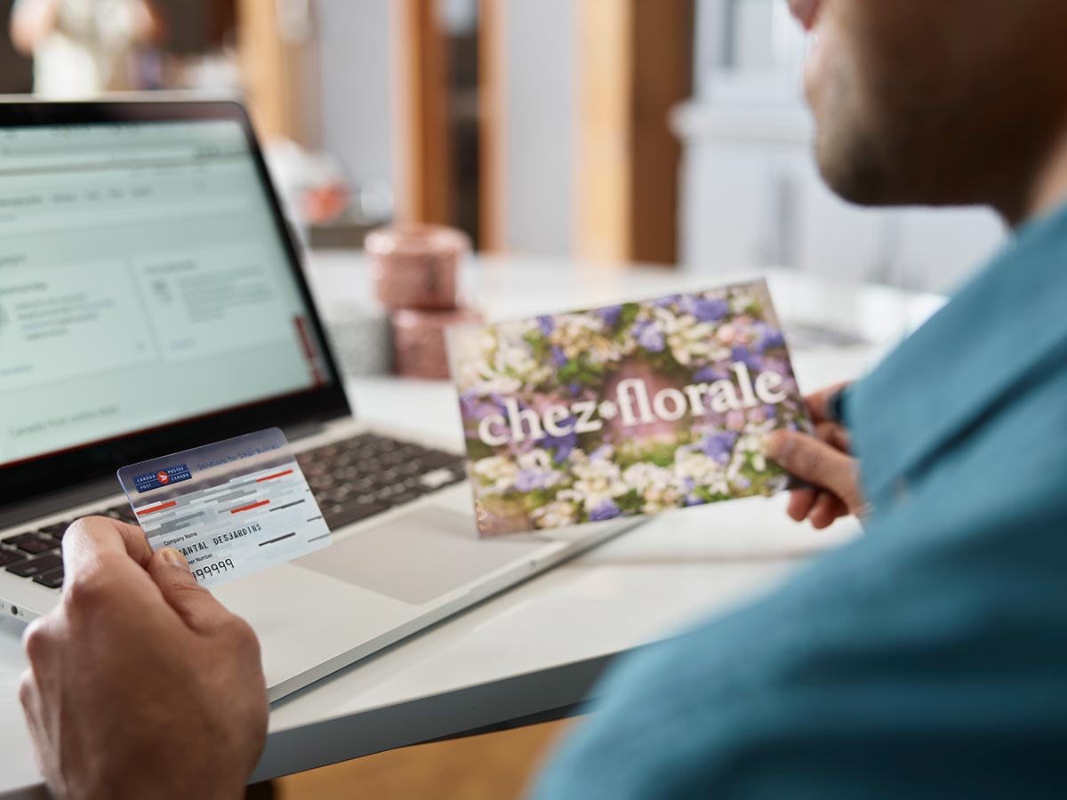 Man holding a Canada Post Solutions for Small Business card and a direct mail item