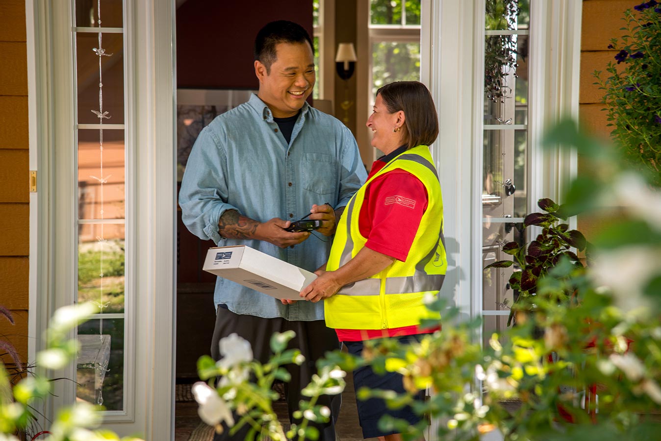 Man being handed a package by a delivery agent and signing for his delivery