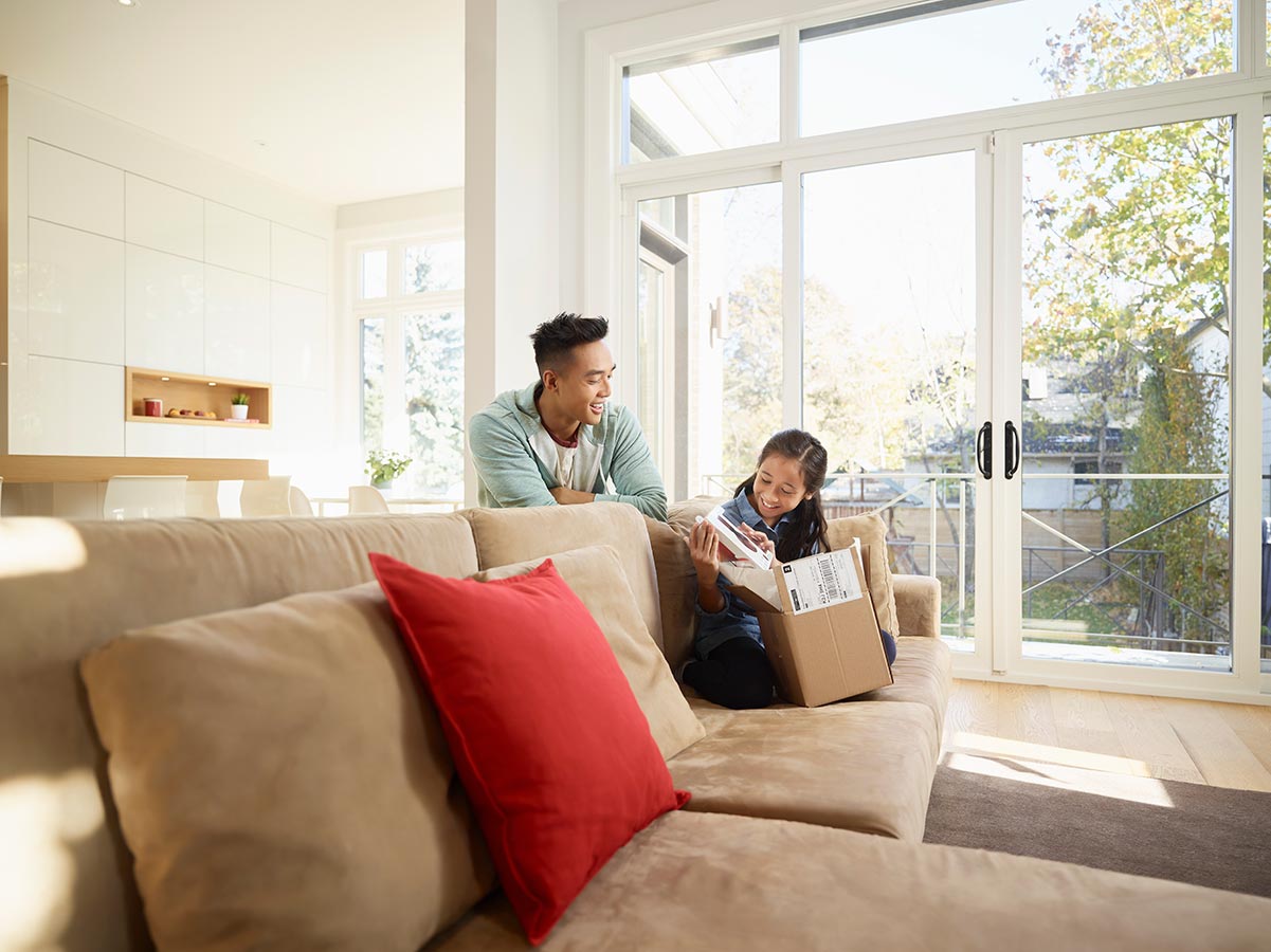 Brother and sister opening a package in a living room