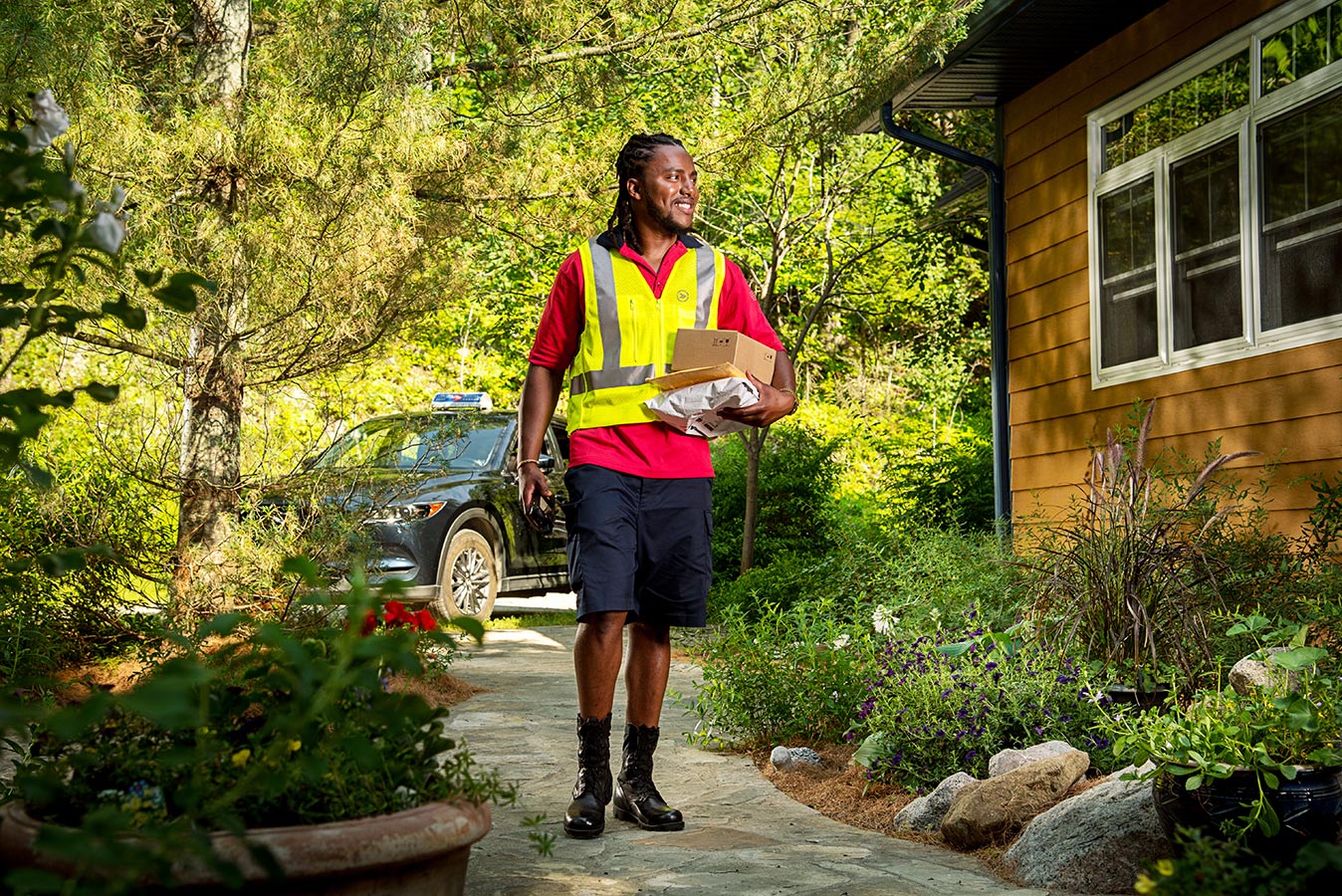 Delivery agent walking packages to a home in a residential neighbourhood