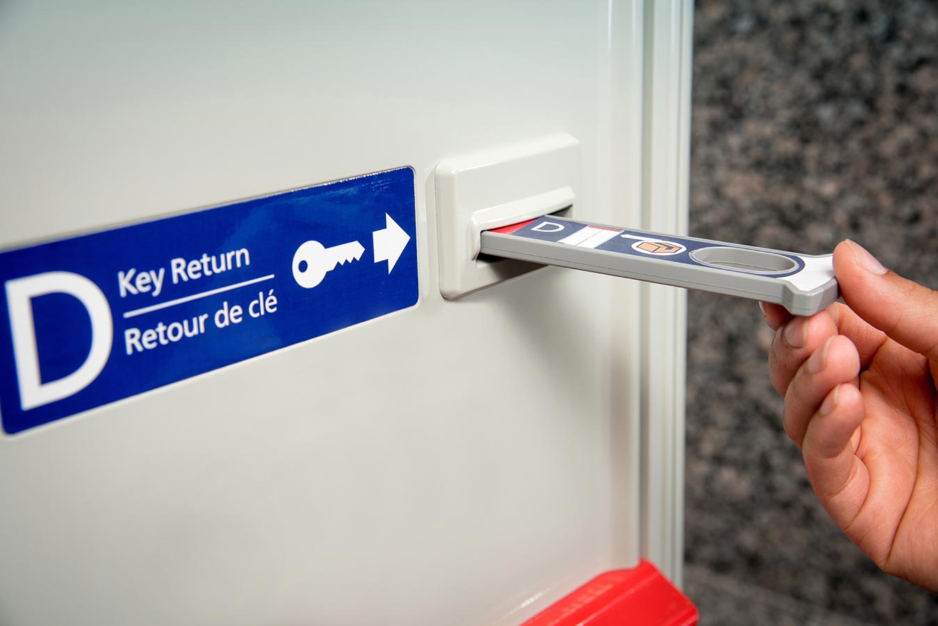 Key being returned to a Canada Post parcel lock through the key return slot