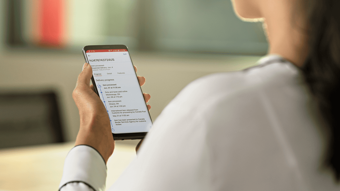 A woman reads Canada Post tracking information on her mobile phone.