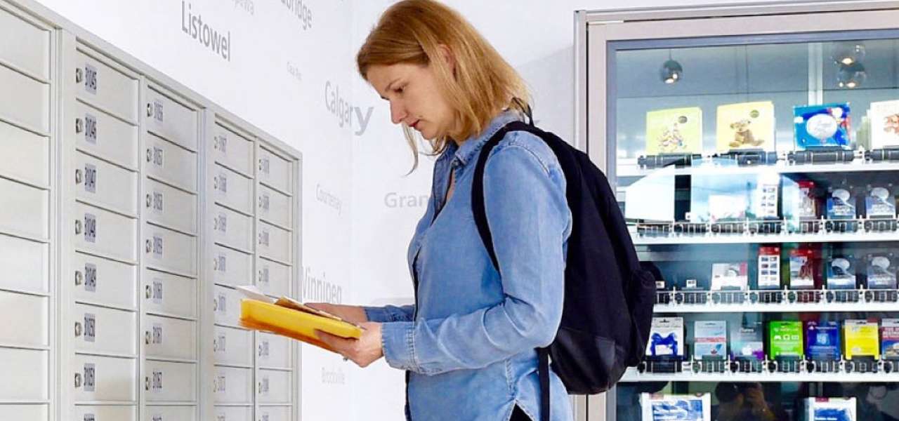 A woman inside a post office sorts through a small stack of mail she has just retrieved from her Canada Post PO box. 