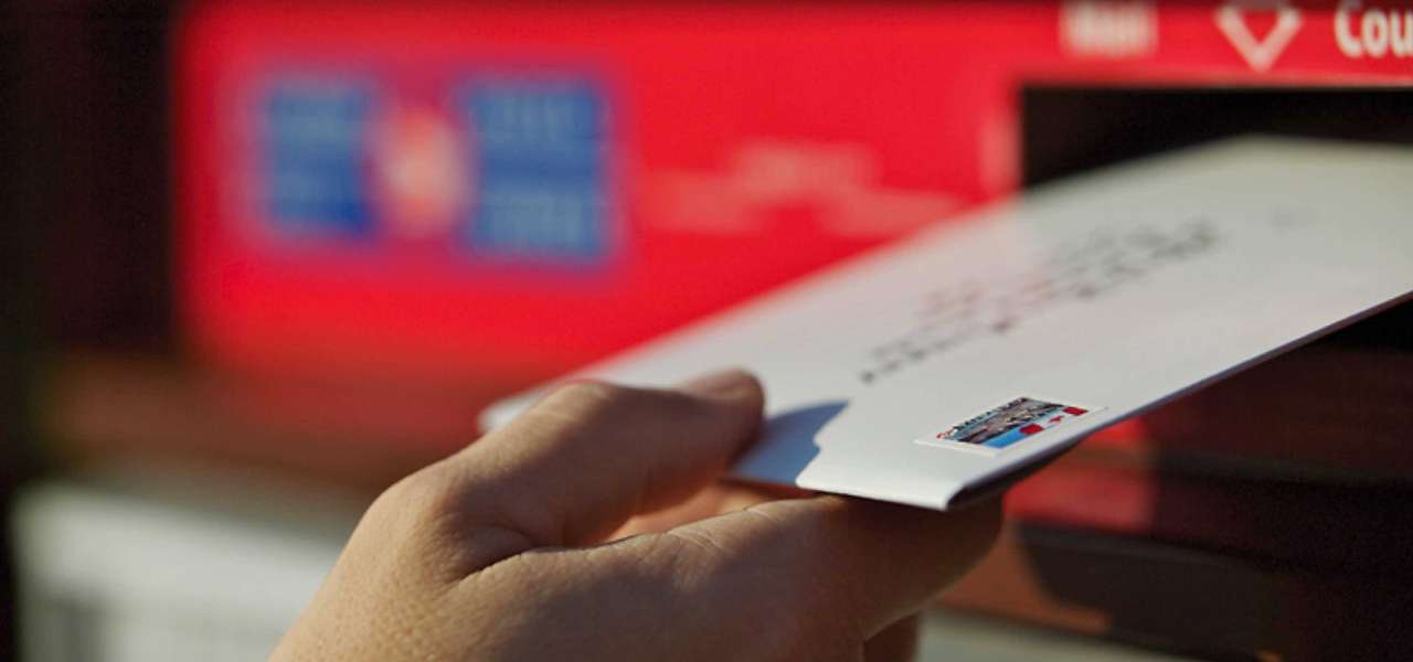 A stamped and addressed envelope is placed in a Canada Post community mailbox to be mailed.