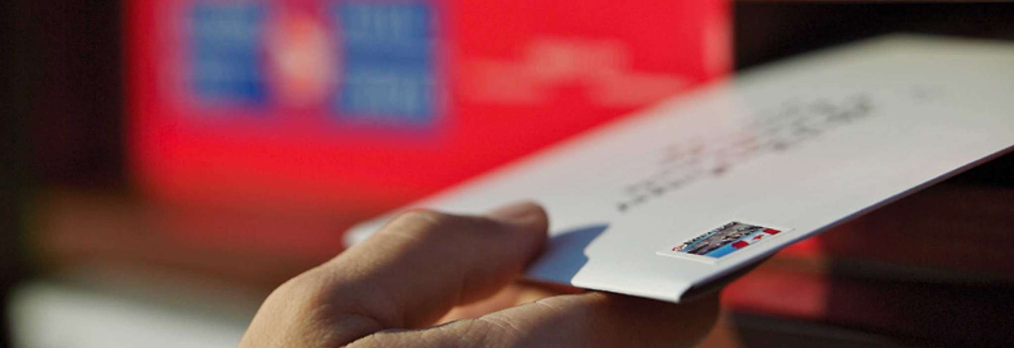 A stamped and addressed envelope is placed in a Canada Post community mailbox to be mailed.