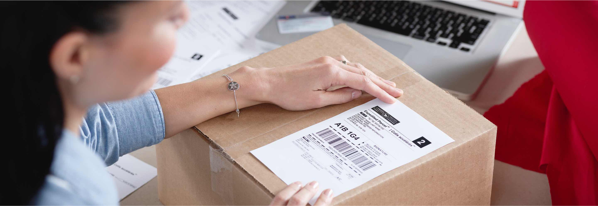 Woman applies a Canada Post return label to a package