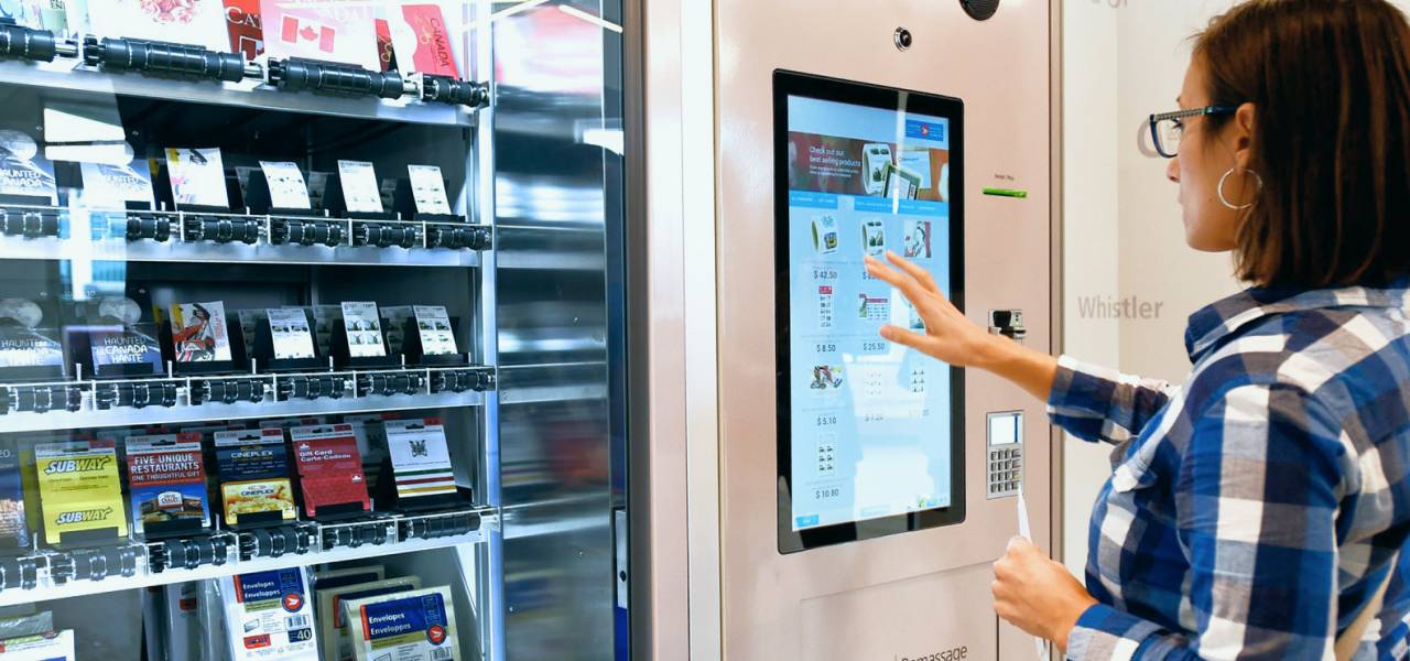 Une femme utilise l’écran tactile d’un distributeur automatique libre-service de Postes Canada pour acheter une carte-cadeau