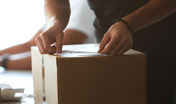 Un homme appose une étiquette d’expédition sur une boîte en carton.