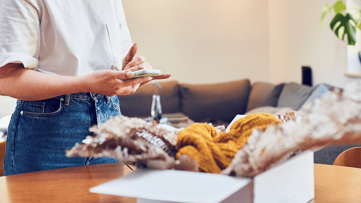 Une femme prépare un colis pour retourner un achat effectué en ligne.