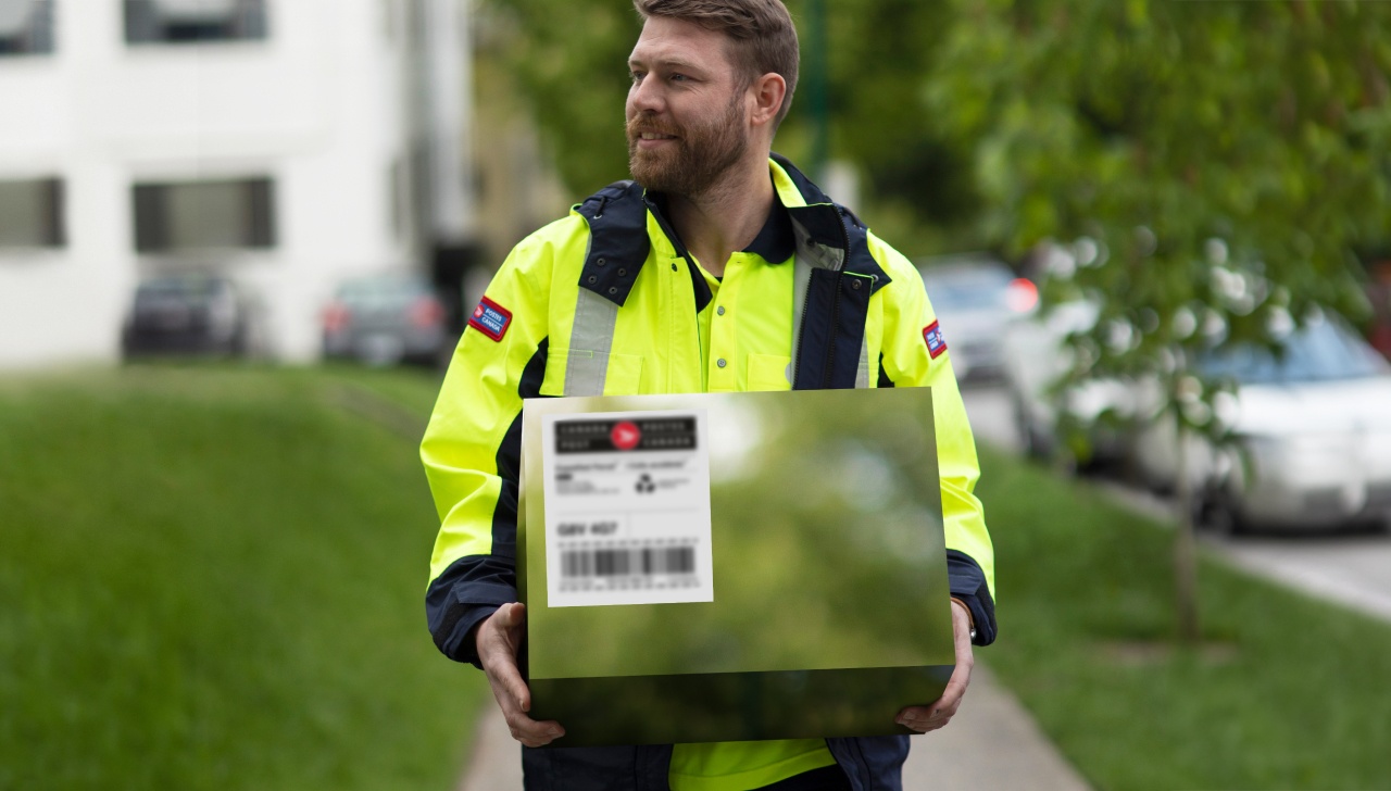 Un employé de Postes Canada tient un colis carboneutre pour le livrer
