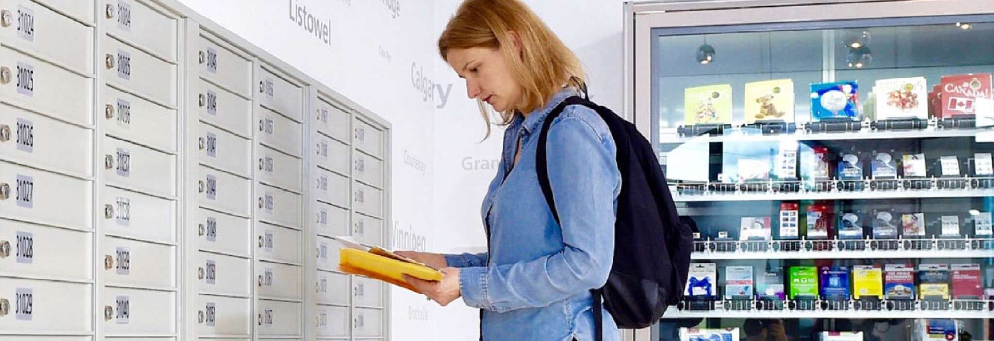 Une femme dans un bureau de poste examine une petite pile de courrier récupérée dans sa case postale de Postes Canada